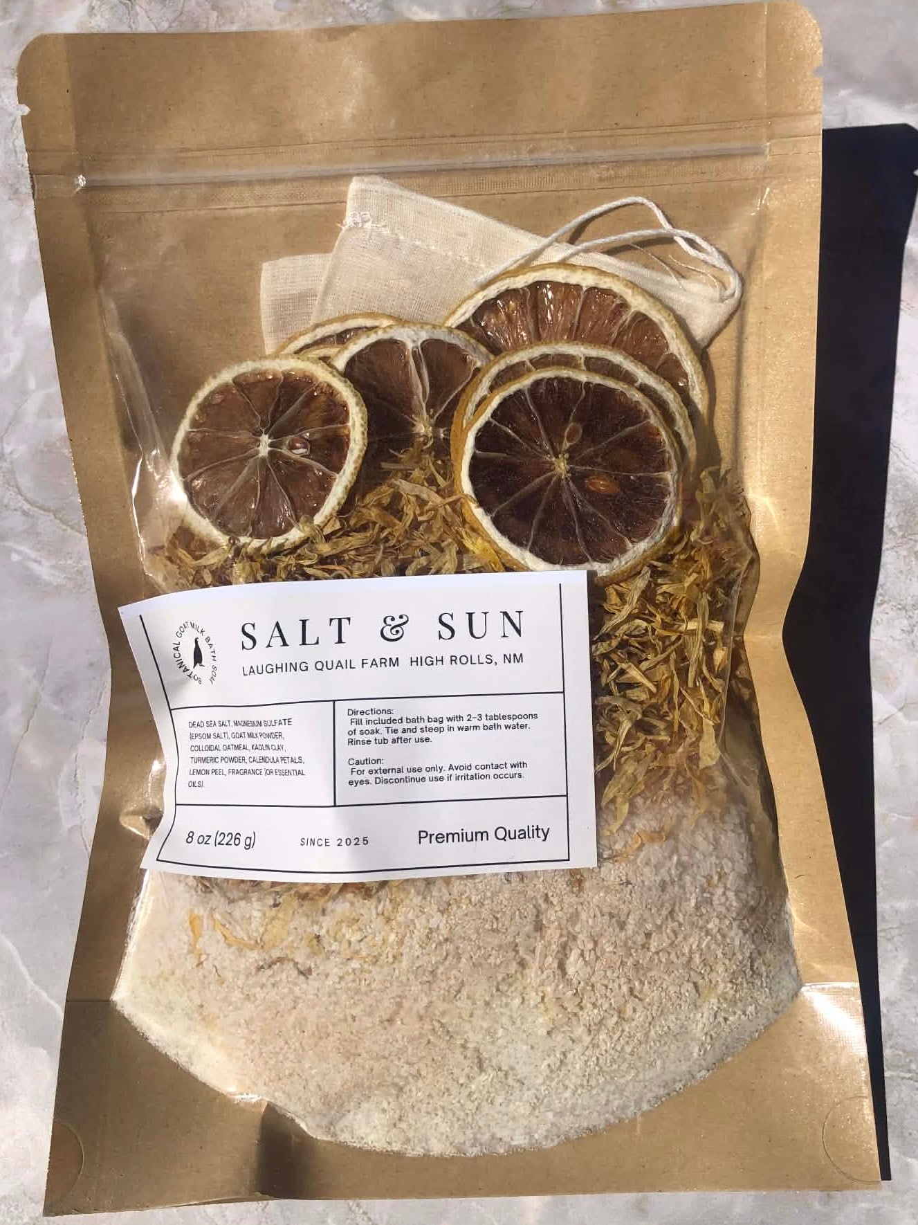 Bag of dried herbs and salt with a 'Salt & Sun' label on a marble surface
