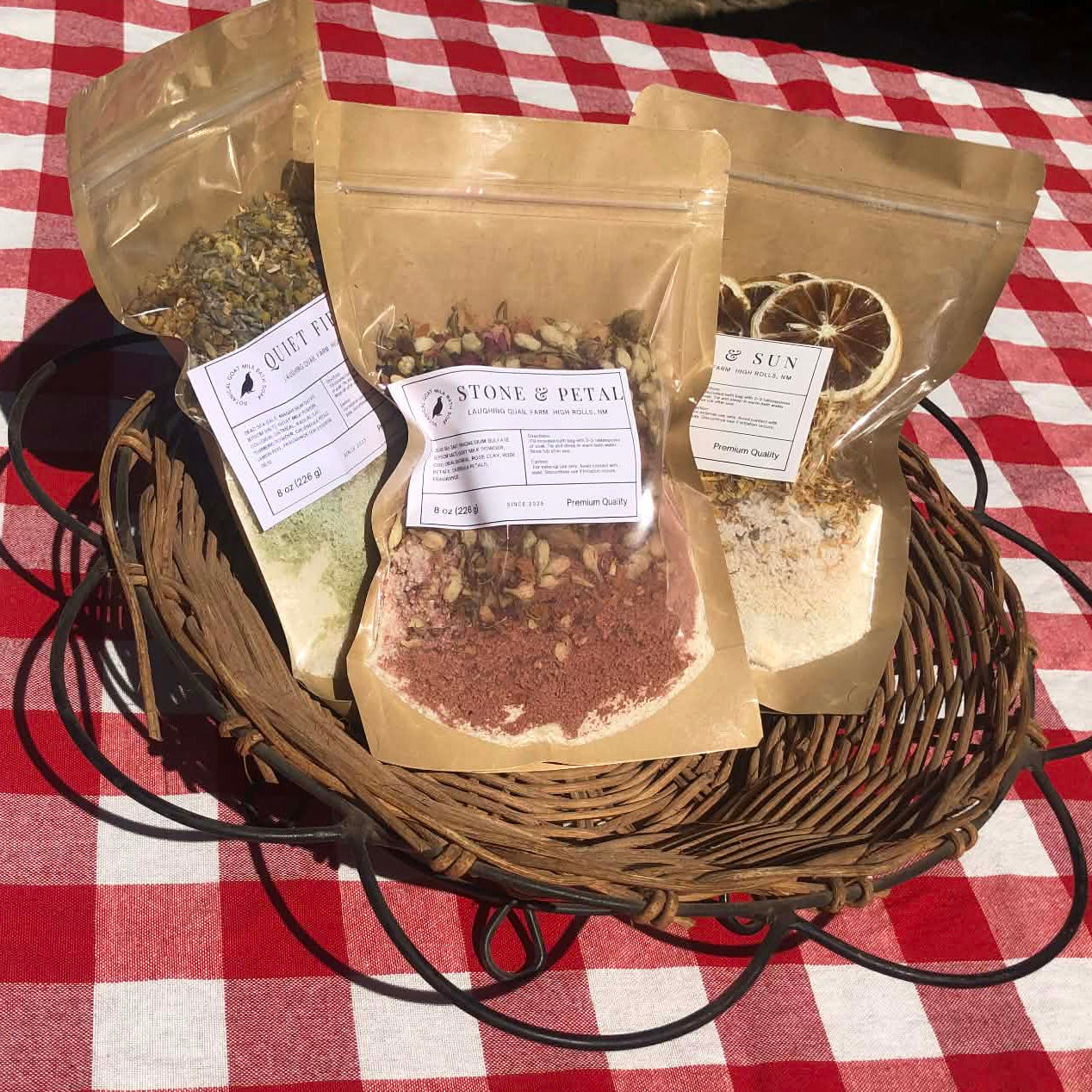 Three brown paper bags with visible text on a red and white checkered tablecloth.